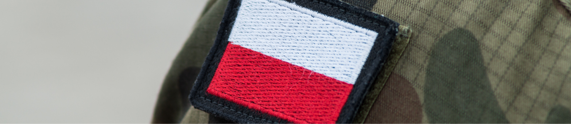 Zbliżenie na flagę Polski znajdującą się na mundurze na ramieniu. 