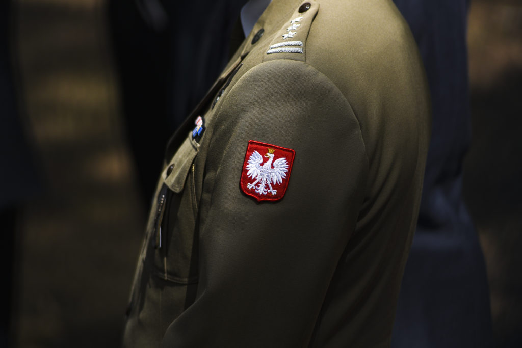Zbliżenie na godło Polski umieszczone na mundurze na lewym ramieniu.
