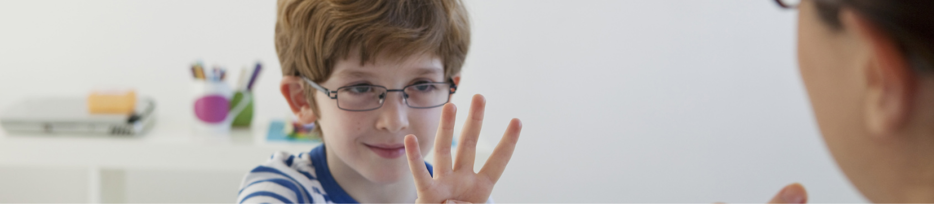 Chłopiec pokazujący liczbę cztery na palcach. 