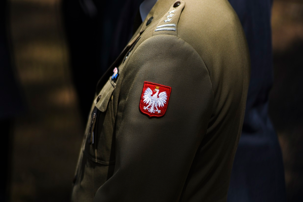 Zbliżenie na godło Polski umieszczone na mundurze na lewym ramieniu.