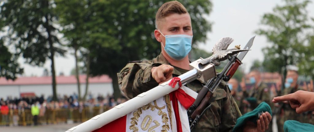 Młody żołnierz składający przysięgę do flagi polskiej.