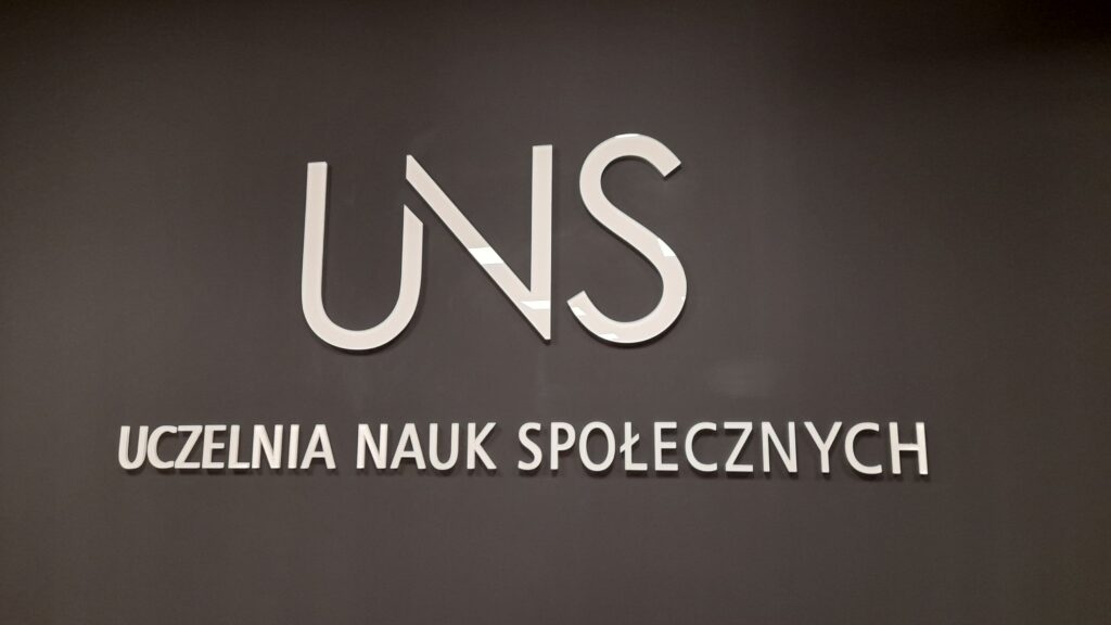 Zdjęcie logotypu UNS na czarnej ścianie