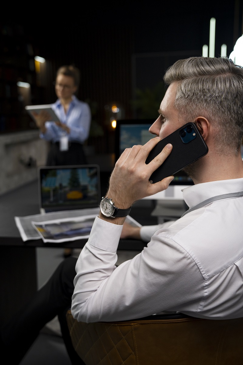 Mężczyzna w białej koszuli rozmawia przez telefon w biurze