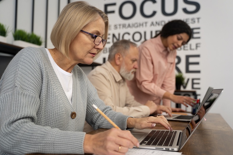Grupa ludzi w średnim wieku ucząca sie przed laptopami