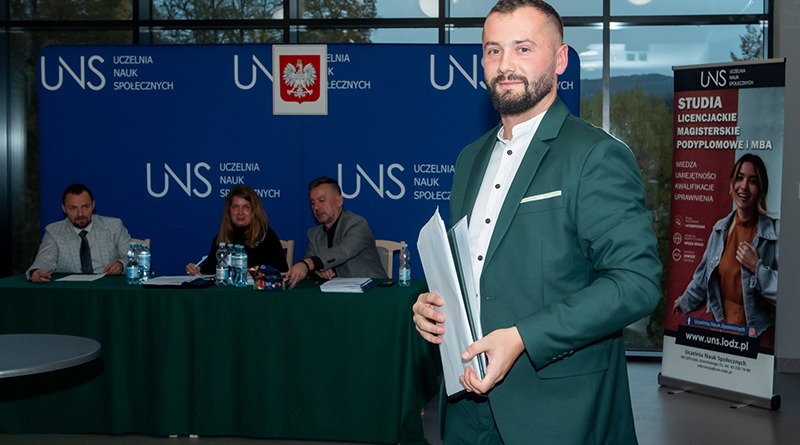 Zdjęcie mężczyzny w garniturze na tle komisji egzaminującej UNS